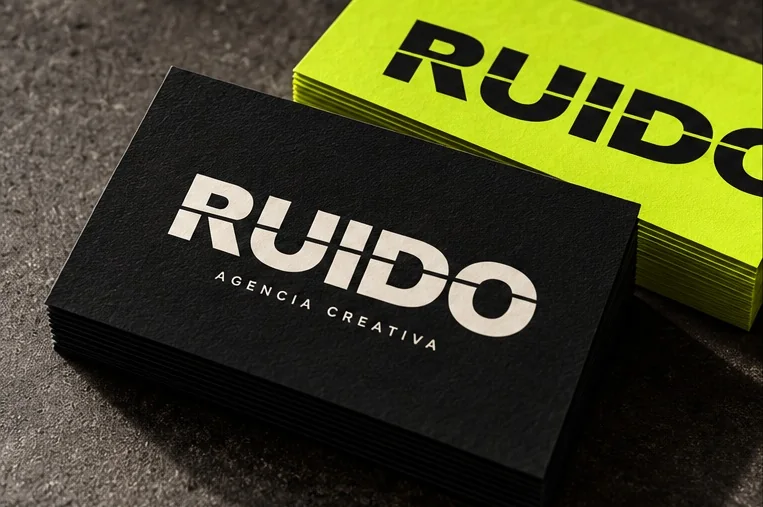 Visualización conceptual de tarjetas personales: frente negro con el logo de RUIDO y reverso verde ácido.